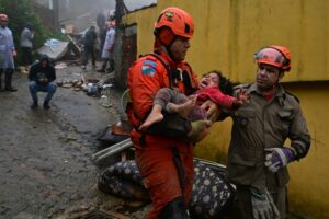 Rescuers carry a girl, who had been trapped for hours under the rubble of her house that was destroyed by heavy rains in Petropolis, Brazil, on March 23, 2024 (Pablo PORCIUNCULA)