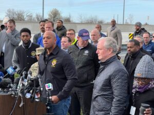 Maryland Gov. Wes Moore steps to the lectern to address the media in Dundalk, Maryland, on March 26, 2024, after the crash and collapse of the Francis Scott Key Bridge. To his right are U.S. Sen. Chris Van Hollen, D-MD, and state and local officials.