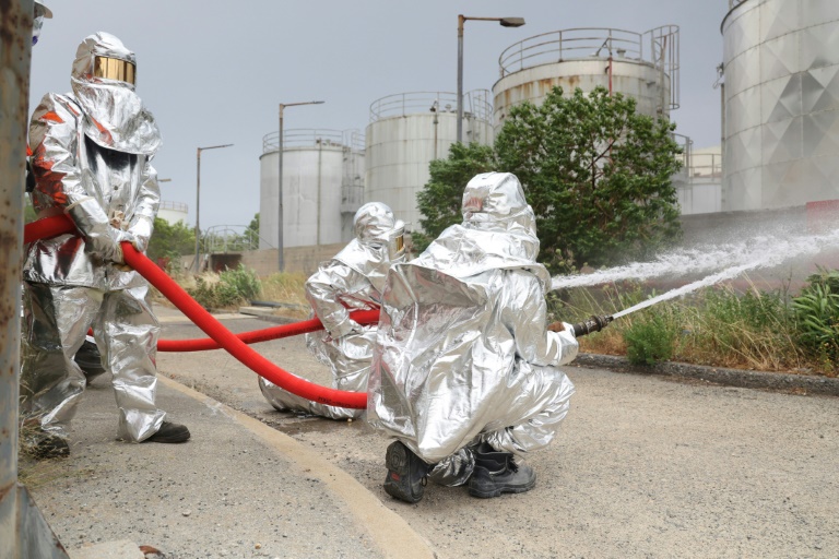 Firefighters in protective gear spray water with hoses as they take part in an earthquake drill (Costas METAXAKIS)
