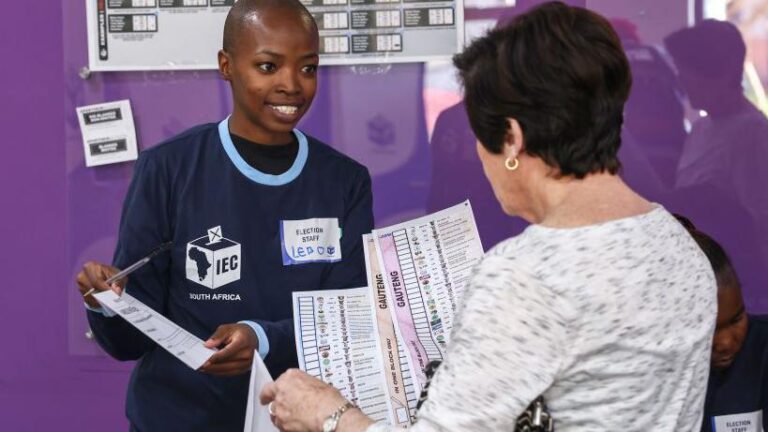  IEC workers present ballots to elderly voters taking part in special early voting at the Reddam House Waterfall School on May 27, 2024 in Midrand, South Africa.