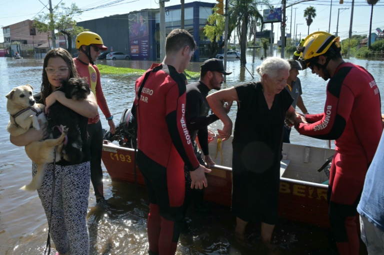 Firefighters help a woman get out of a boat in the flooded Brazilian city of Porto Alegre on May 6, 2024 (NELSON ALMEIDA)