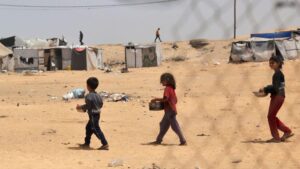 File photo showing displaced Palestinian children carrying containers with food in Rafah, in the southern Gaza Strip (19 May 2024)