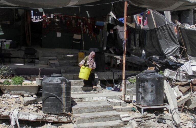 A Palestinian woman walks among the rubble of a damaged building, in Beit Lahia